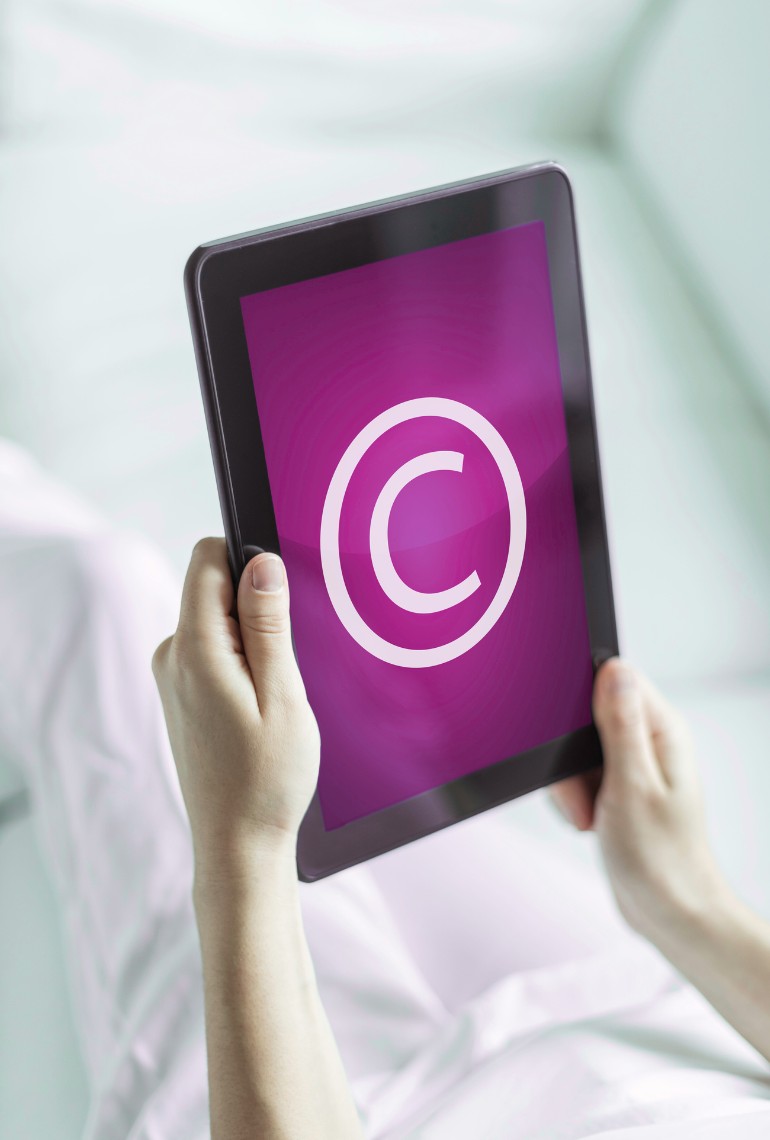 Tablette affichant un symbole copyright, illustrant la protection des œuvres et l’horodatage de documents par la technologie blockchain