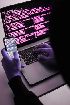 Person using a laptop displaying code and a smartphone, illustrating digital automation, APIs and data certification using blockchain technology